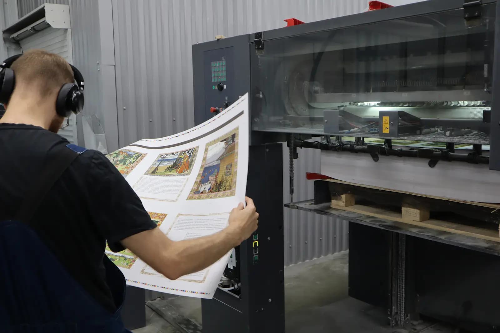 Специалист печатного цеха проверяет качество печати визуально