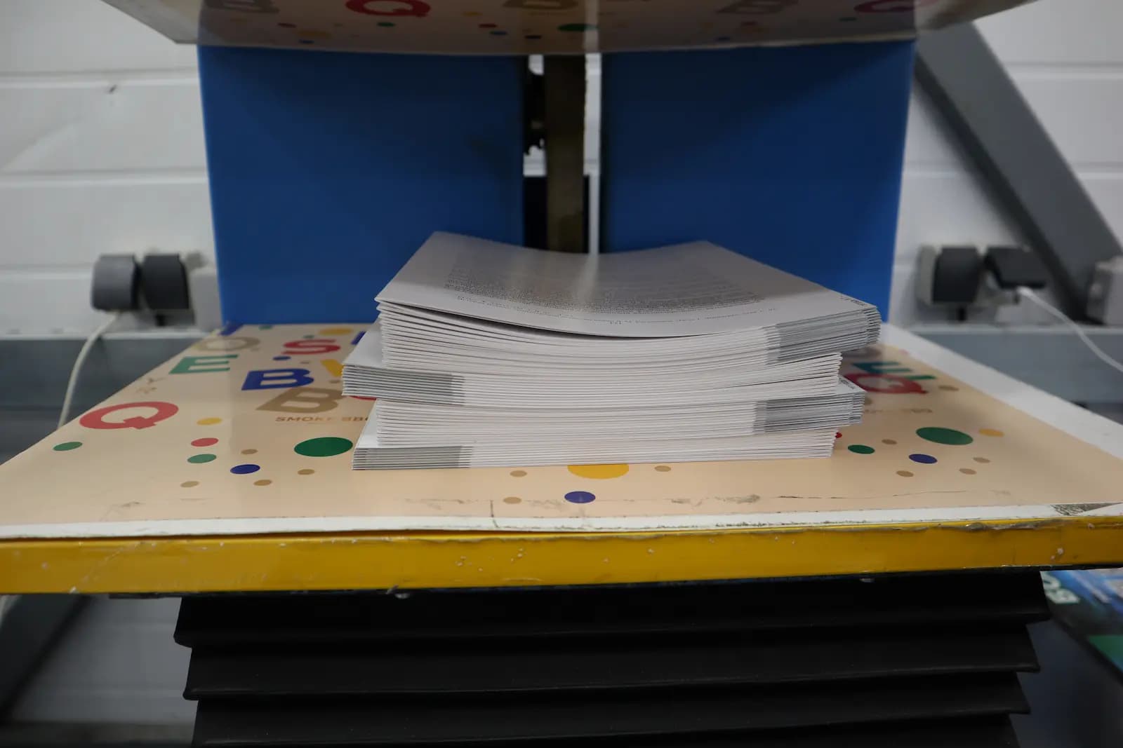 Листы тетрадей лежат на аппарате для прессования